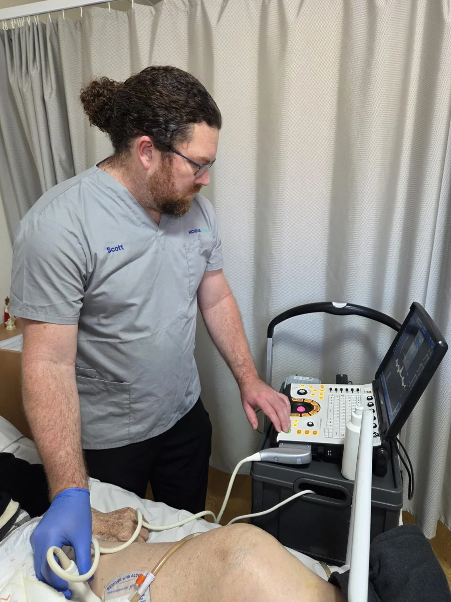 Modia Health sonographer performing a bedside abdominal ultrasound with a portable scanner